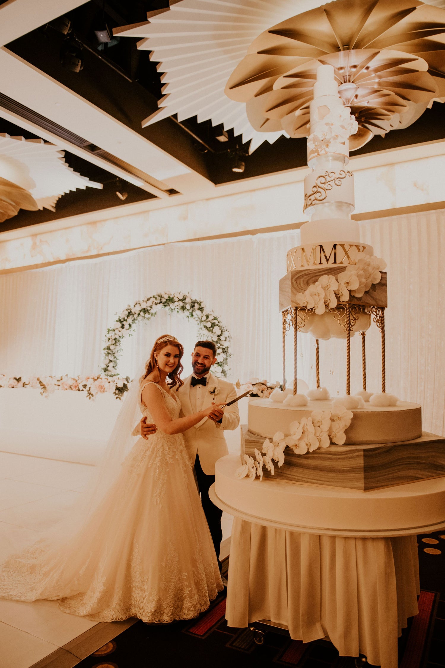 Wedding couple cutting Perth's Tallest wedding cake in a decorated room.