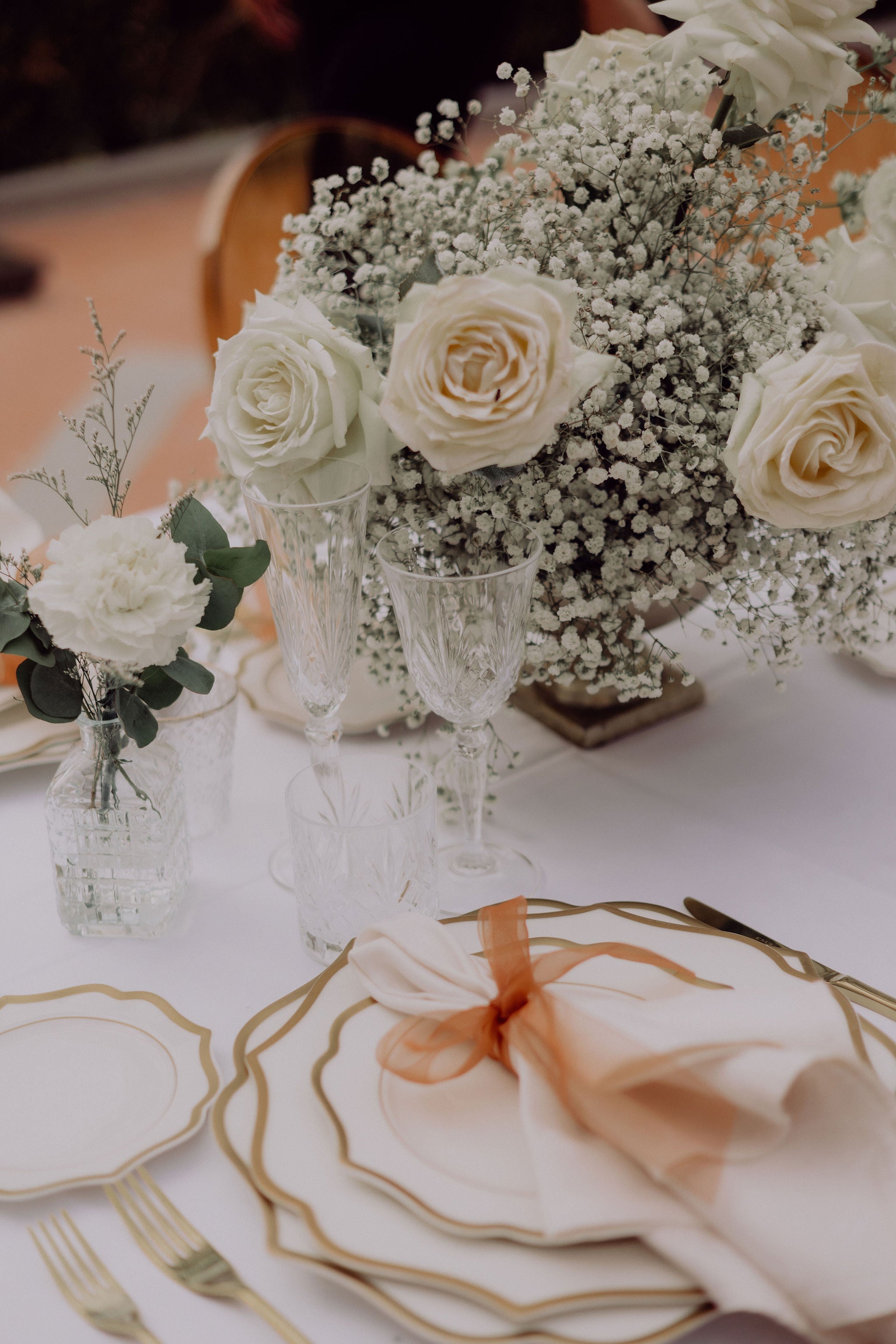 Luxury white and gold wedding tablescape with roses and crystal glassware