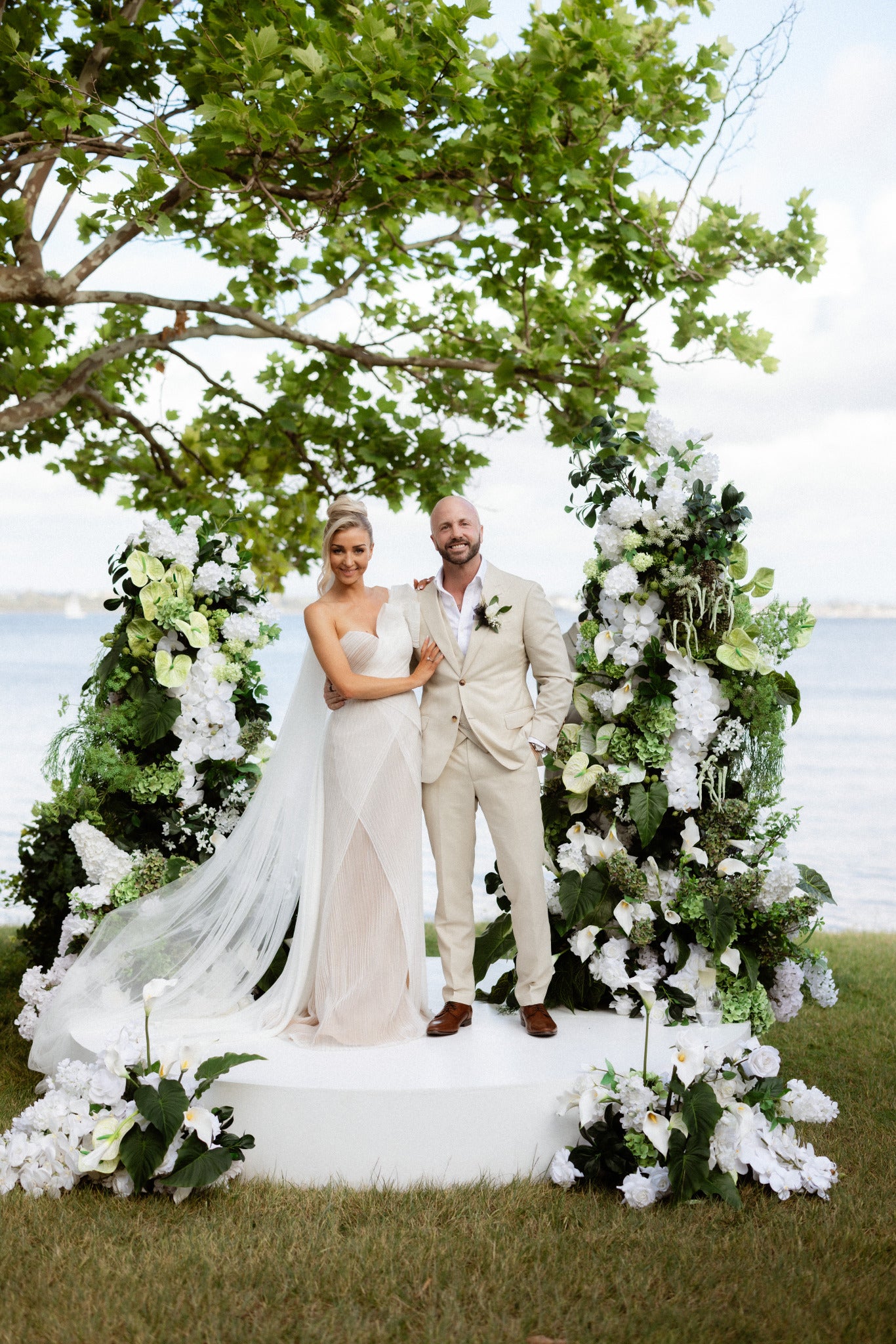 Perth Wedding couple standing under a floral arch with a scenic background