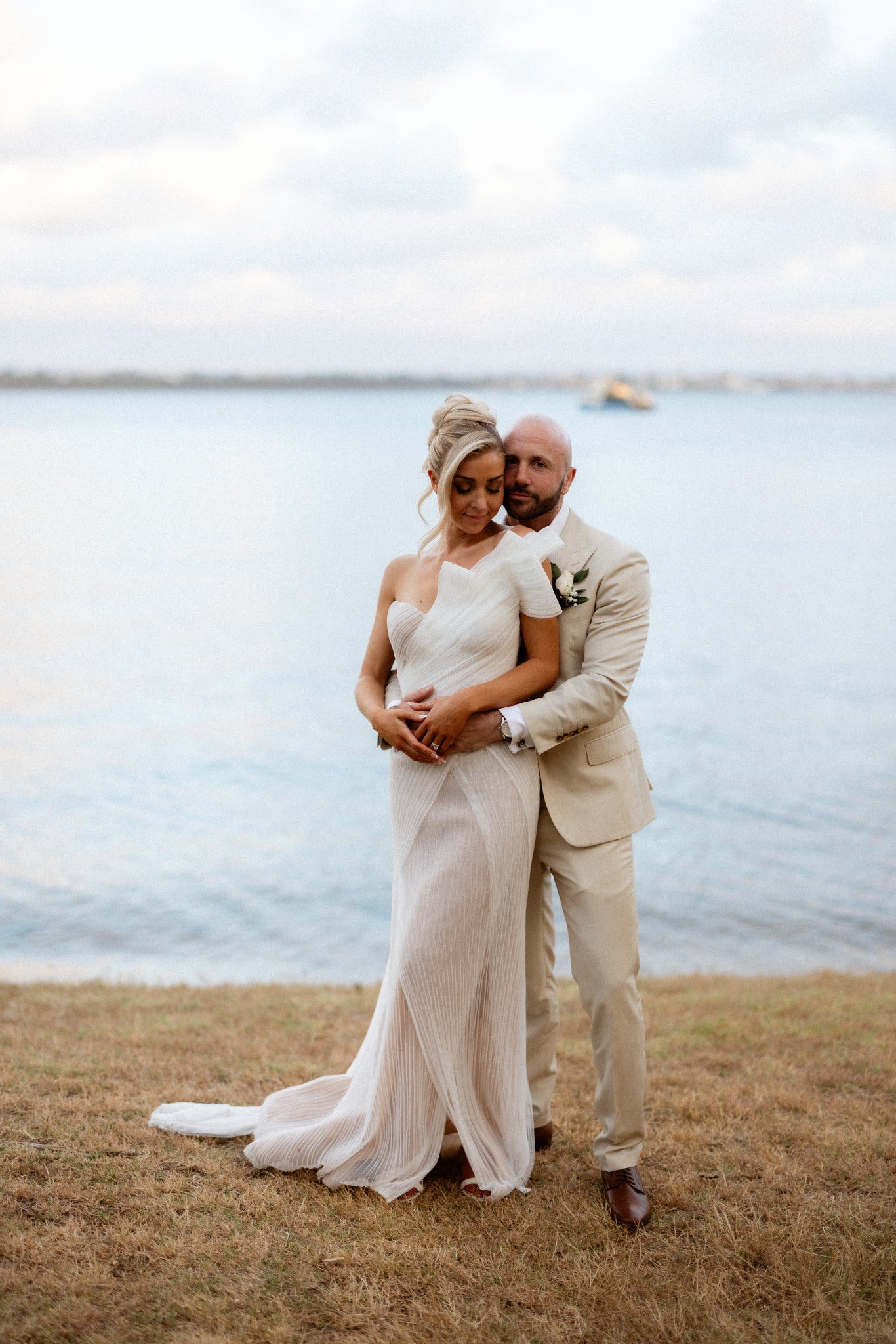 Couple in wedding attire standing on a grassy area by Matilda Bay Reserve on the Swan River. 